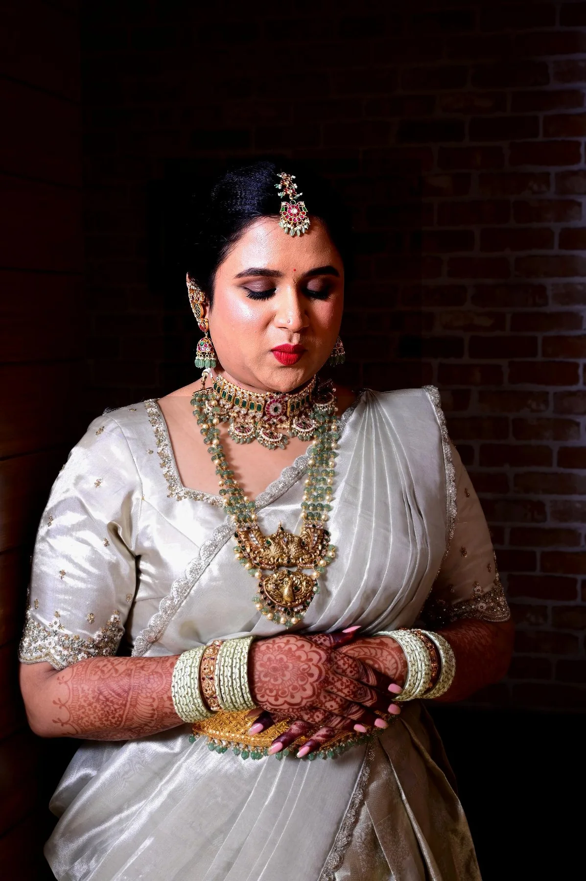Bride in a white saree with traditional jewellery and mehendi